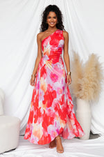 Woman wearing a colorful one-shoulder dress in a minimal indoor setting.