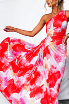 Woman wearing a colorful one-shoulder dress with a floral pattern on a white background