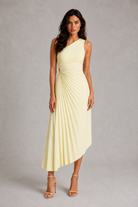 Woman wearing a light yellow one-shoulder dress on a gray background
