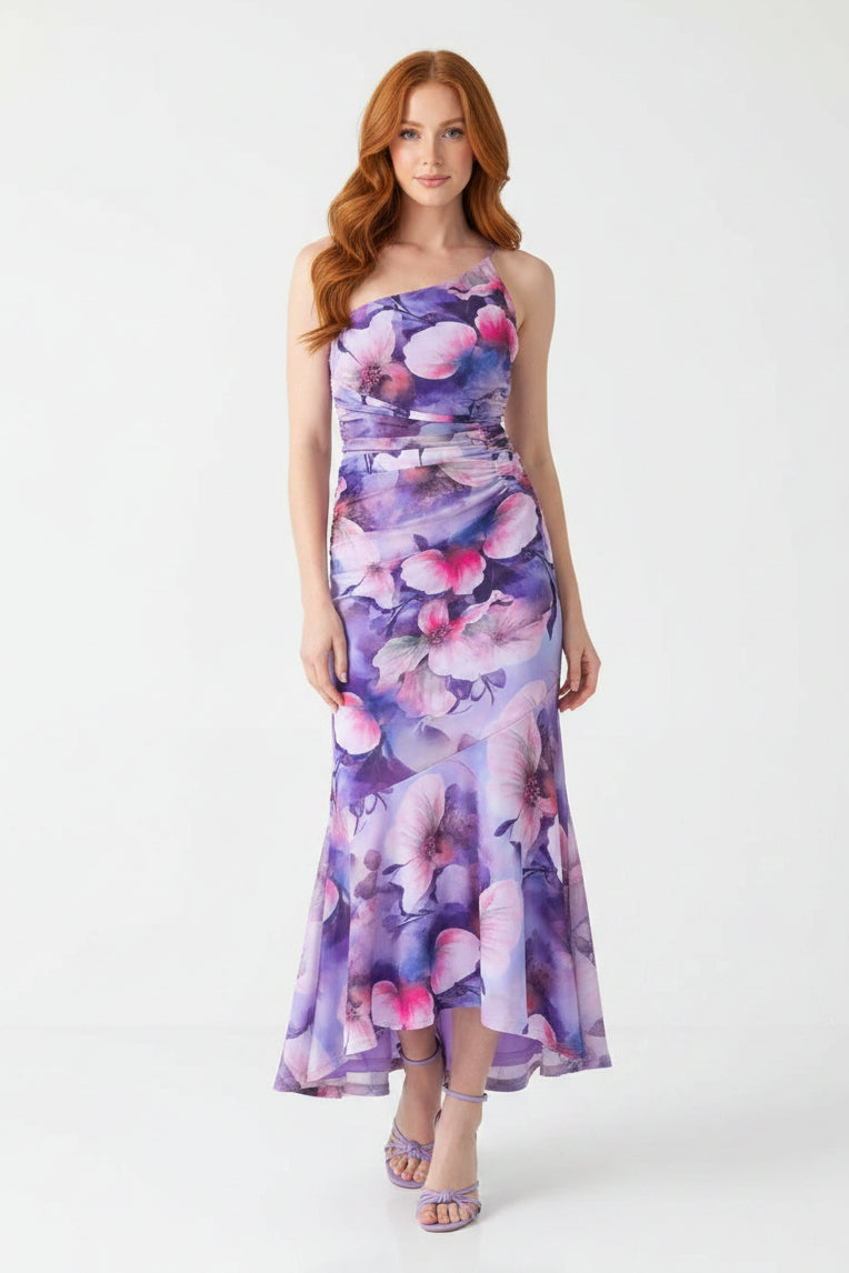 Woman wearing a floral one-shoulder dress against a gray background