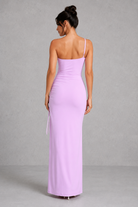Woman wearing a long lavender dress against a gray background