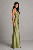 Woman wearing a green satin gown against a gray background
