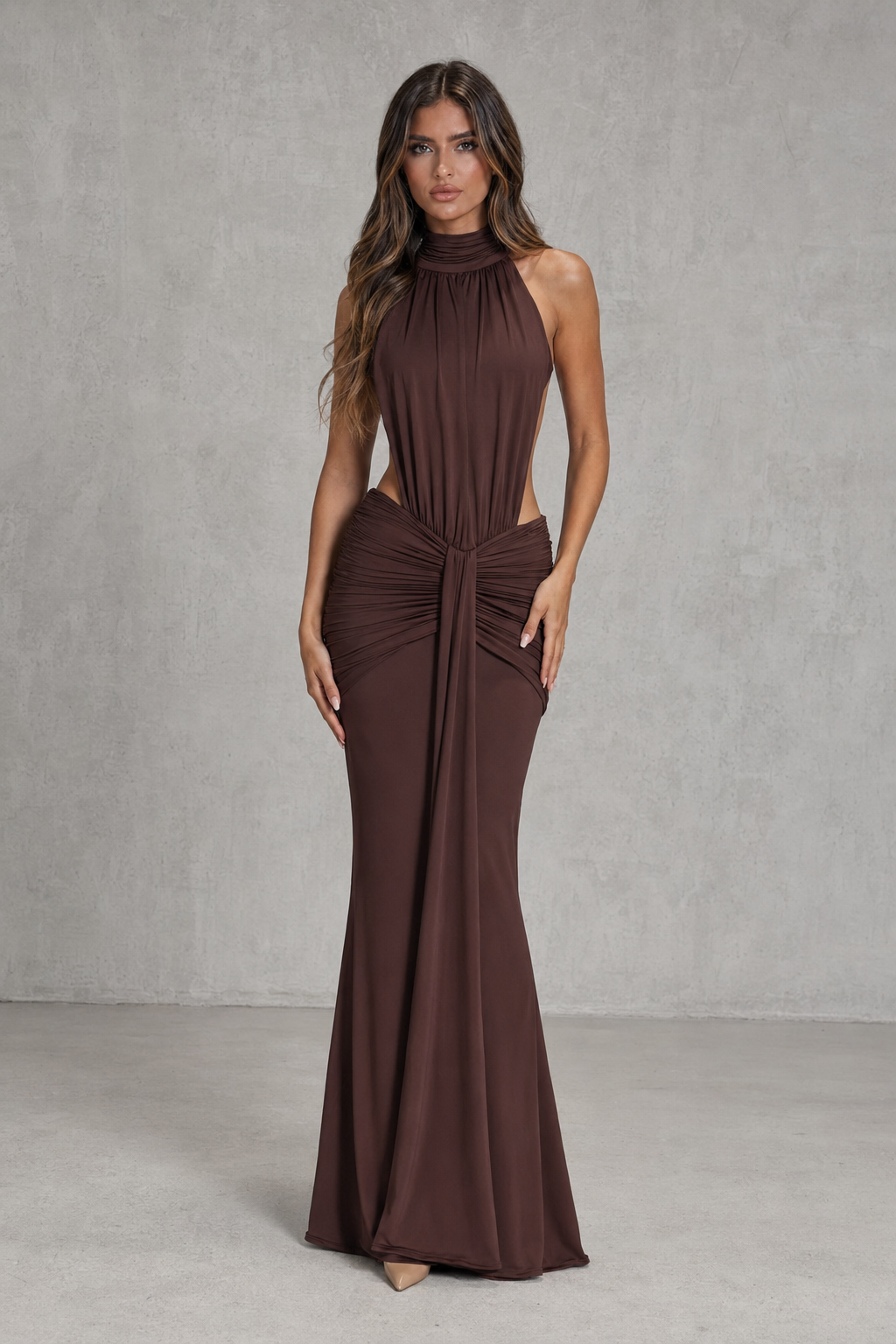 Woman wearing a brown halter neck gown against a plain background