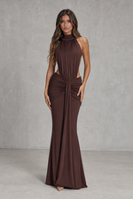Woman wearing a brown halter neck gown against a plain background