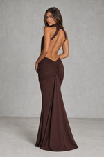 Woman wearing a brown evening gown with an open back against a gray background