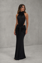Woman wearing a black halter neck gown against a gray background