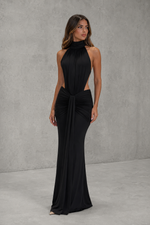 Woman wearing a black halter neck gown against a gray background