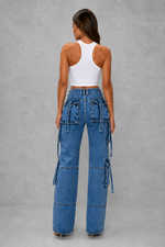Woman wearing blue cargo pants and a white top on a gray background
