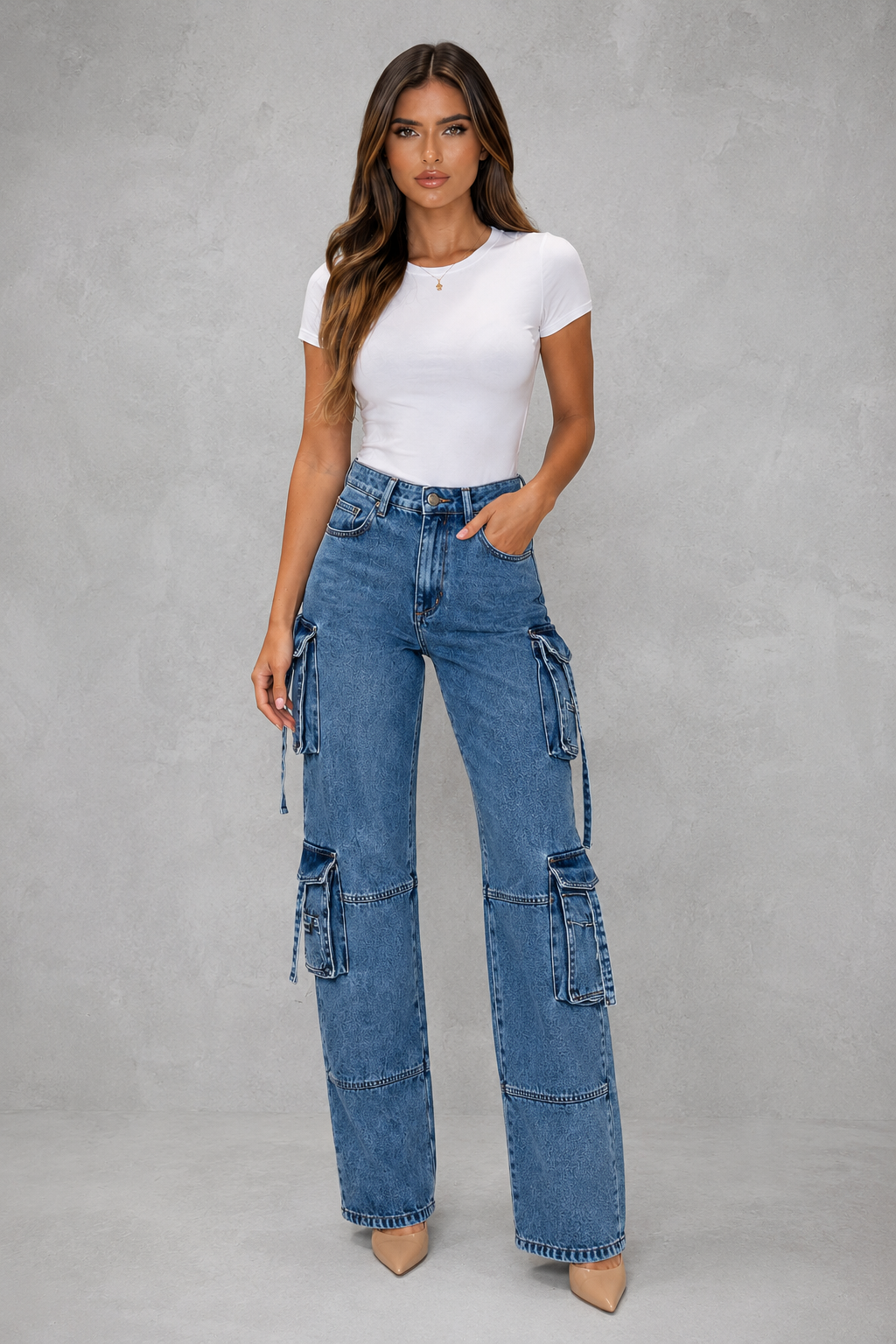 Woman wearing a white t-shirt and blue cargo jeans against a gray background