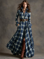 Woman wearing a long blue plaid dress with brown boots against a gray background