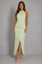 Woman wearing a light green halter neck dress against a gray background