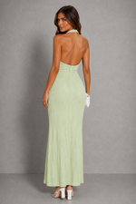 Woman wearing a light green halter neck dress against a gray background
