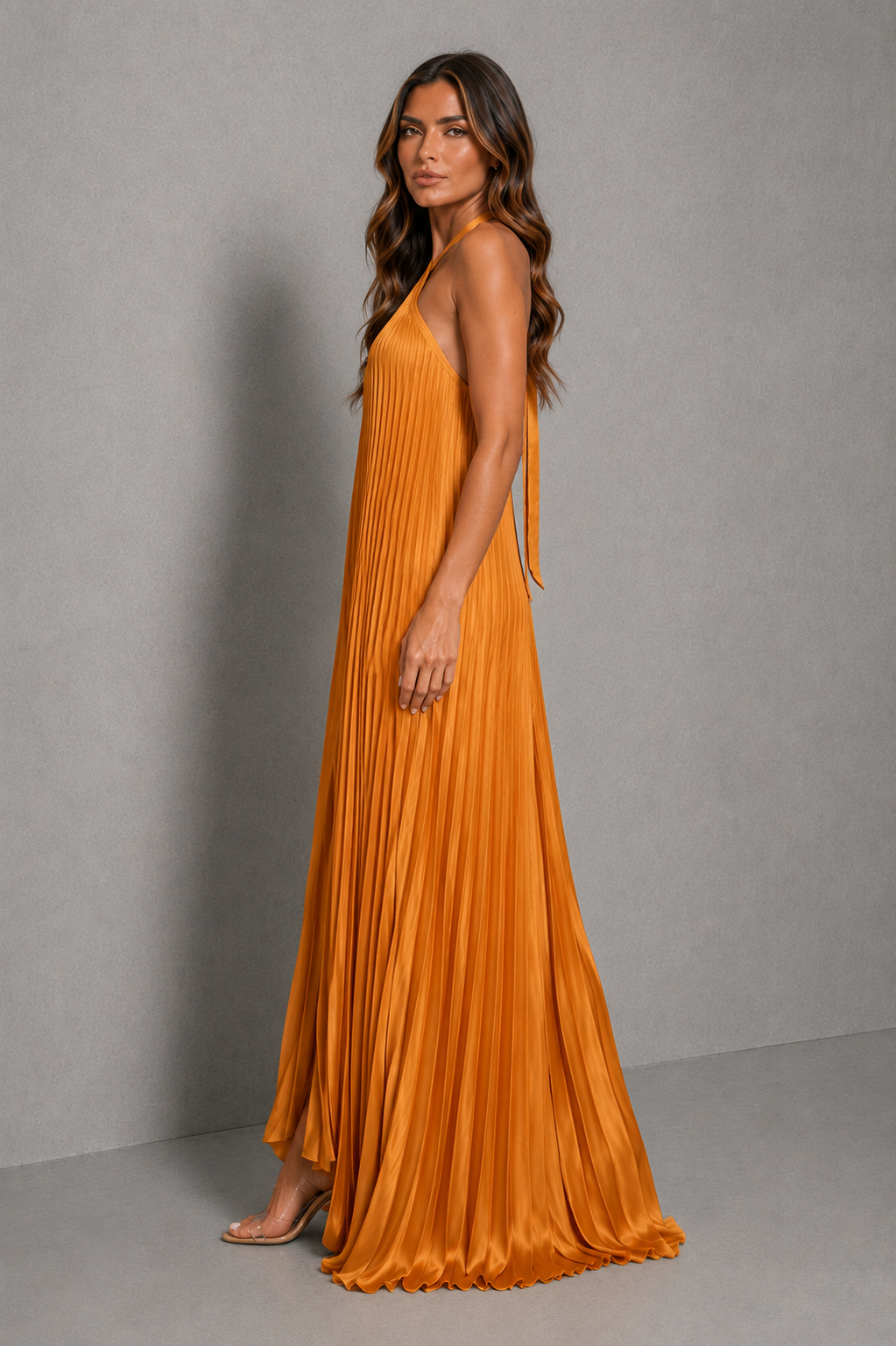 Women’s golden orange pleated halterneck maxi dress with a cross-front neckline, open back, and flowing floor-length silhouette for wedding guests and formal occasions