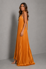 Women’s golden orange pleated halterneck maxi dress with a cross-front neckline, open back, and flowing floor-length silhouette for wedding guests and formal occasions