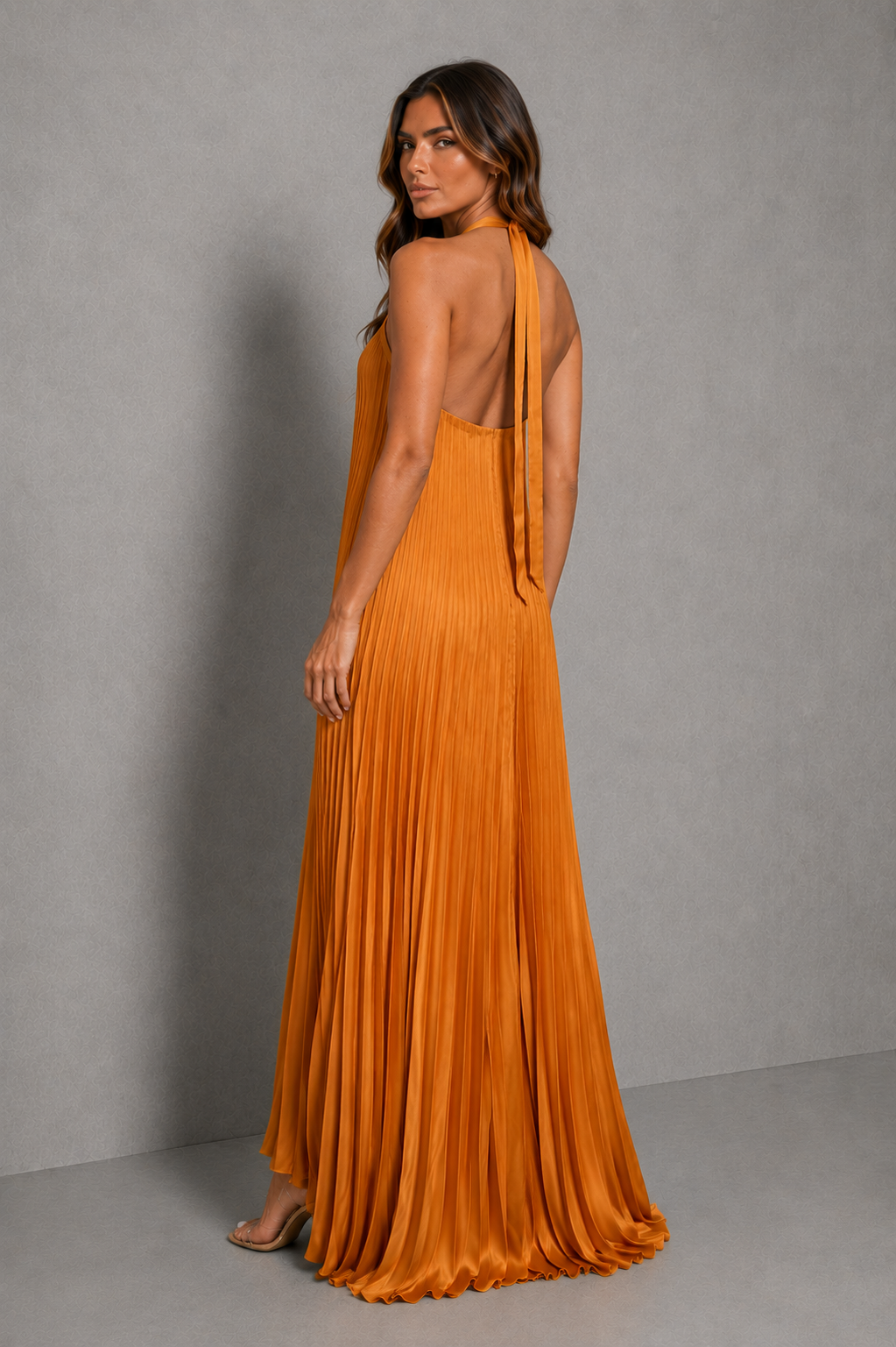 Women’s golden orange pleated halterneck maxi dress with a cross-front neckline, open back, and flowing floor-length silhouette for wedding guests and formal occasions