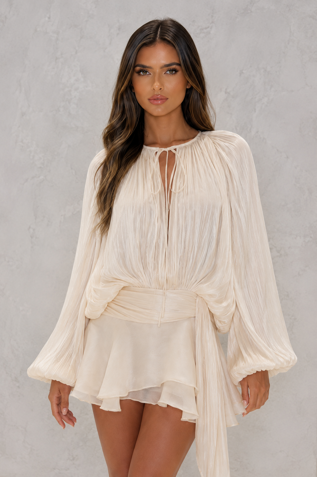 Woman wearing a beige long-sleeve dress against a gray background