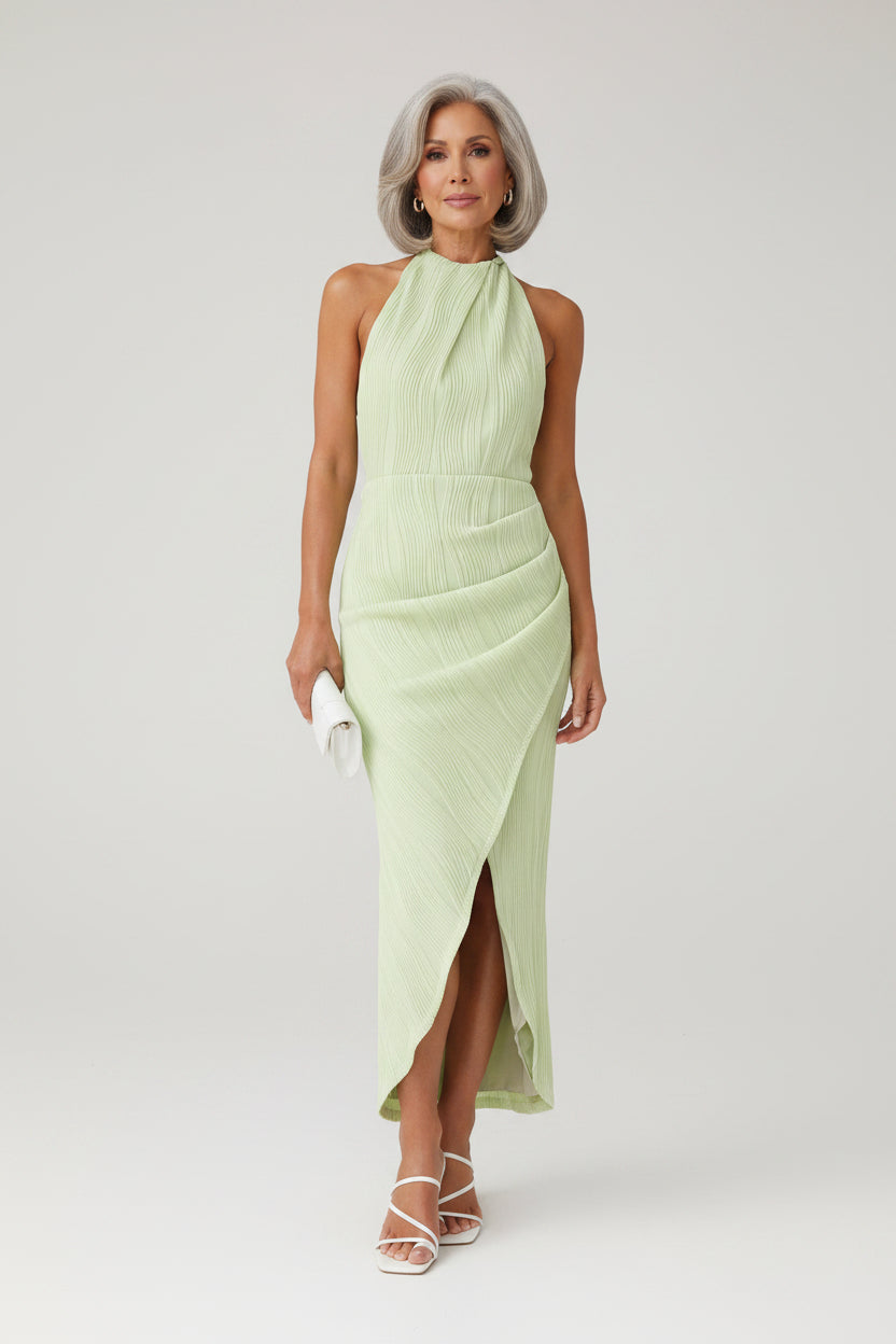 Woman wearing a light green dress against a stone wall.