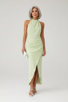 Woman wearing a light green dress against a stone wall.
