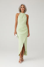 Woman wearing a light green dress against a stone wall.
