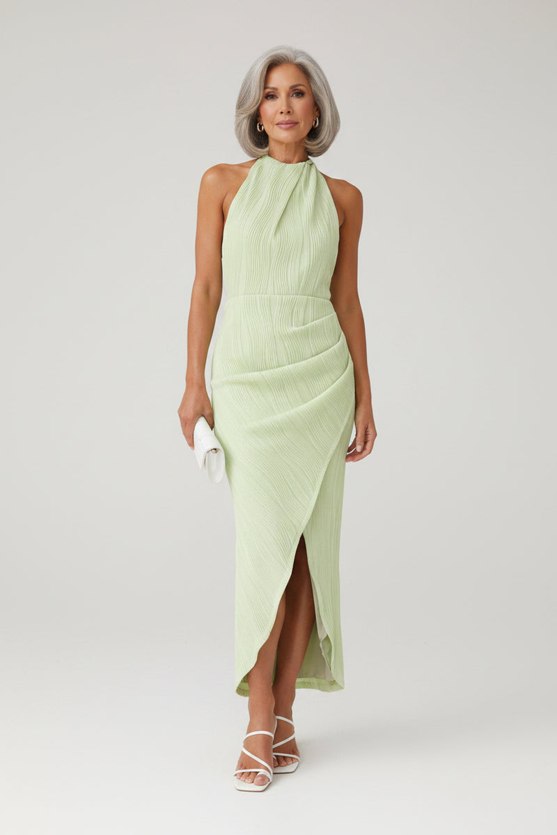 Woman wearing a light green dress against a stone wall.