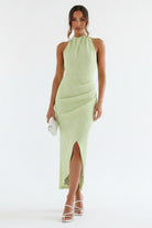 Woman wearing a light green dress with a stone wall background