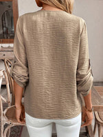Person wearing a beige long-sleeve top in an indoor setting