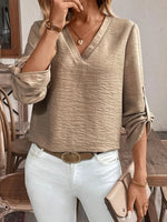 Woman wearing a beige sweater and white pants in an indoor setting