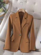 Brown blazer on a hanger against a neutral background