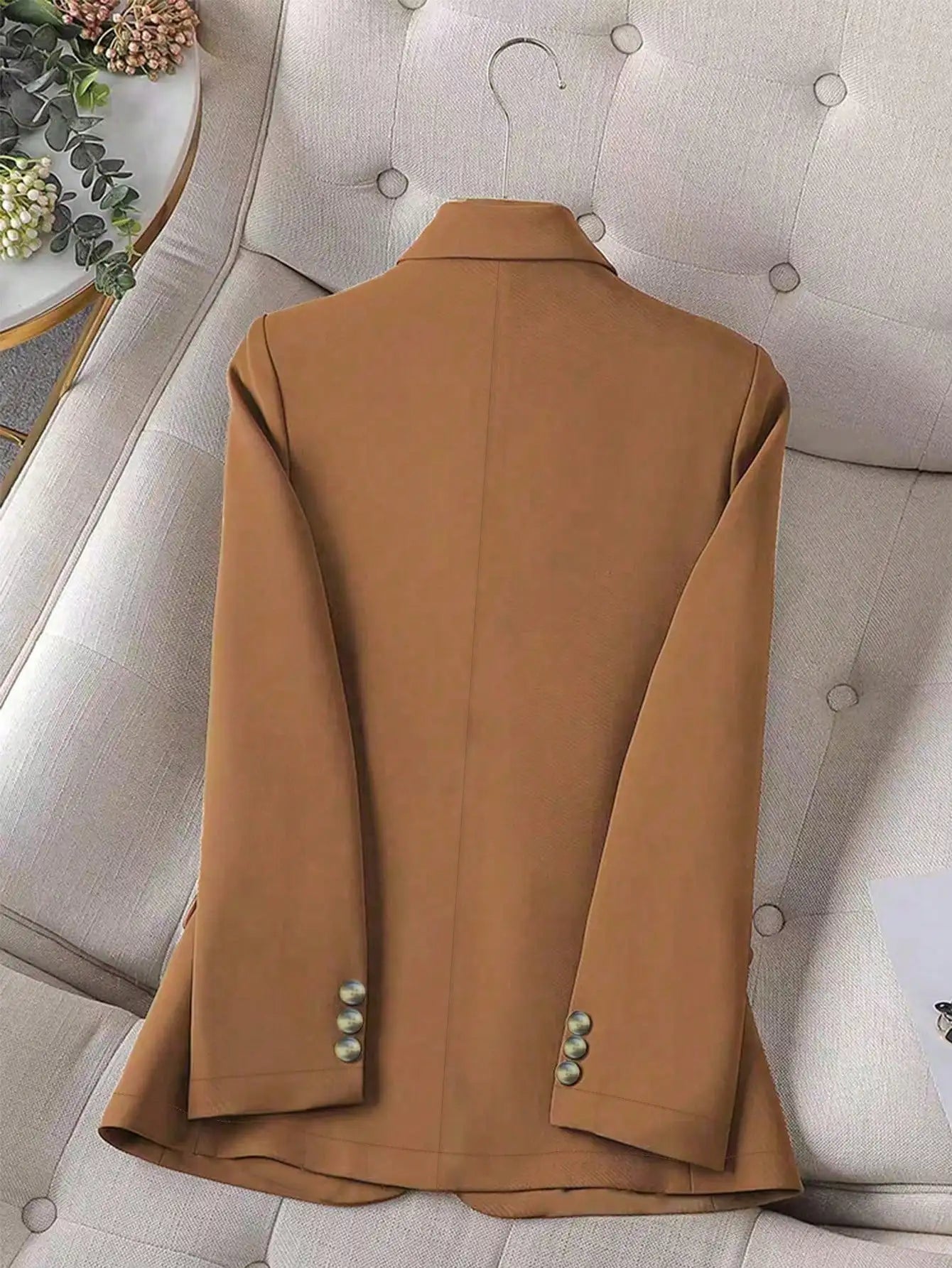 Brown coat on a gray sofa with decorative elements in the background