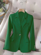 Green blazer on a hanger against a neutral background