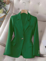 Green blazer on a hanger against a neutral background