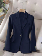 Navy blue blazer on a hanger against a neutral background