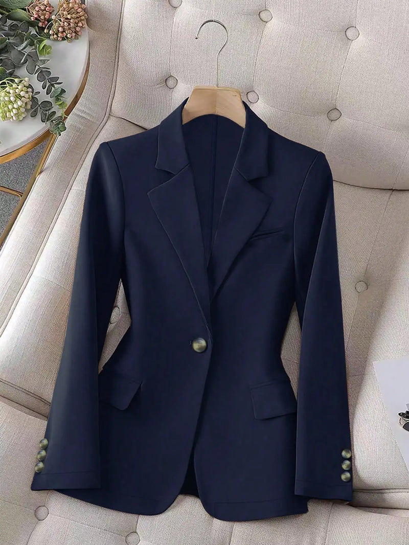 Navy blue blazer on a hanger against a neutral background