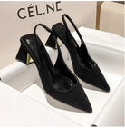 Black pointed-toe high-heeled shoes on a white surface with 'Cél.è' branding in the background.