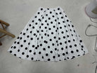 White skirt with black polka dots on a light gray floor.