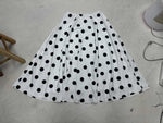 White skirt with black polka dots on a light gray floor.
