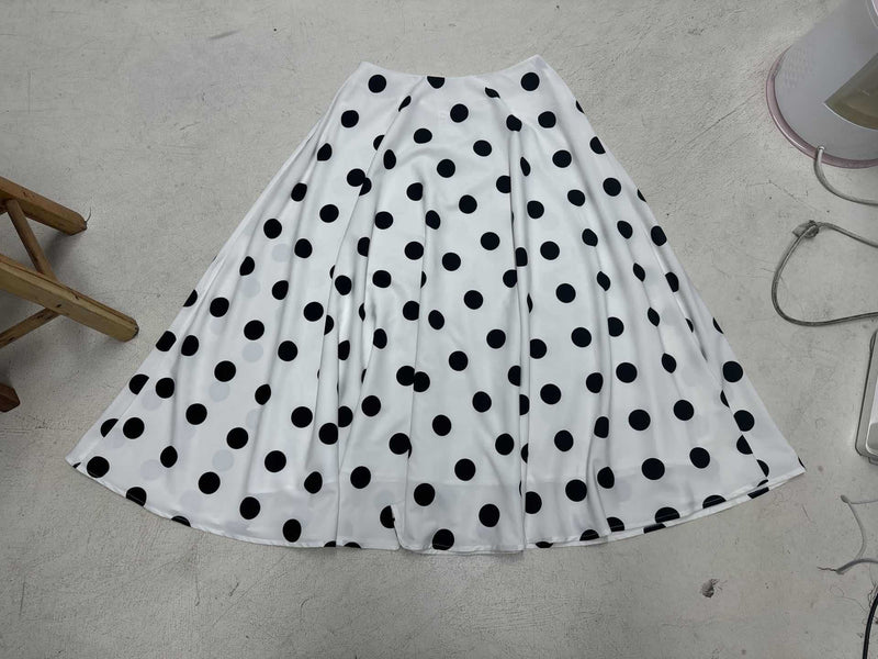 White skirt with black polka dots on a light gray floor.