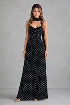 Woman wearing a black strapless dress with white polka dots against a gray background