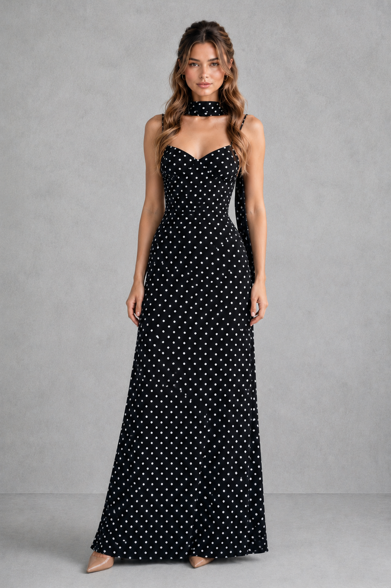 Woman wearing a black strapless dress with white polka dots against a gray background