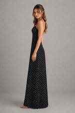 Woman wearing a black polka dot dress against a gray background