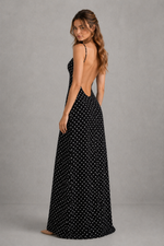 Woman wearing a black polka dot dress with a gray background