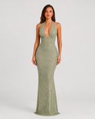 Woman wearing a green beaded halter neck dress against a plain background
