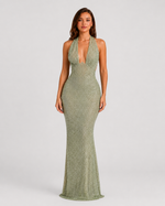 Woman wearing a green beaded halter neck dress against a plain background