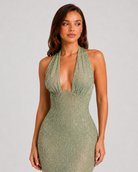 Woman wearing a green beaded halter neck dress against a plain background
