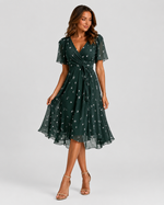 Woman wearing a green dress with a subtle pattern on a gray background