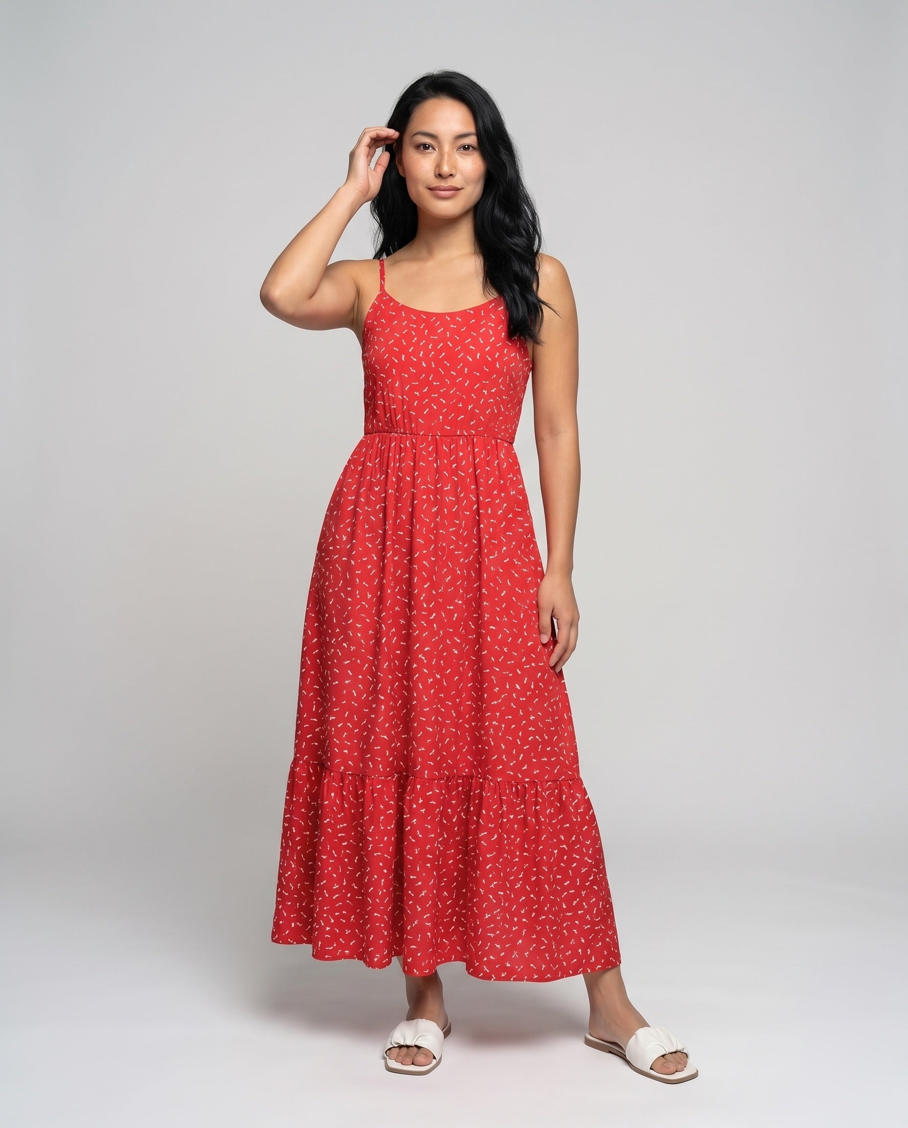 Woman wearing a red dress with white patterns on a gray background