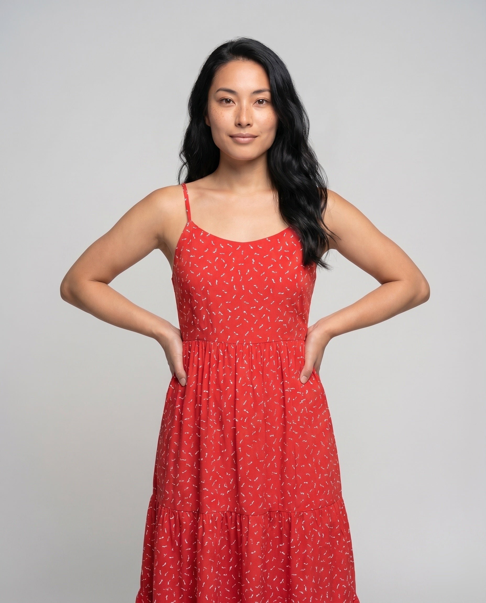 Woman wearing a red dress with a white pattern on a gray background