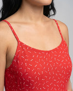Red sleeveless top with white patterns worn by a person on a gray background