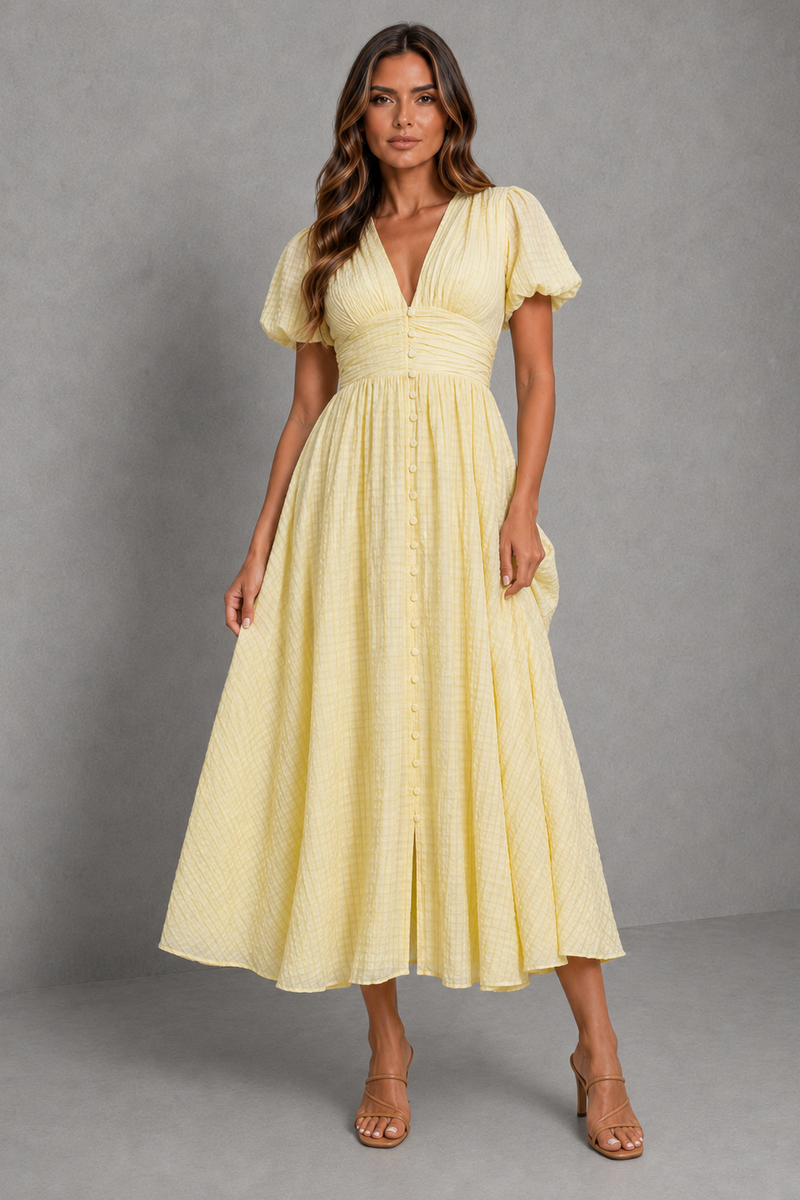 A woman modeling a pale yellow midi dress with puff sleeves, a V-neckline, and a gathered empire waist, set against a neutral gray studio backdrop.