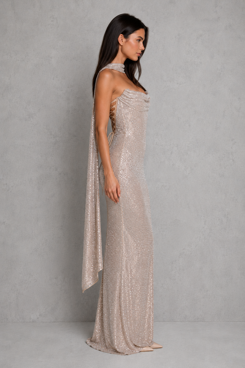 Woman wearing a sparkly, strapless gown against a plain background